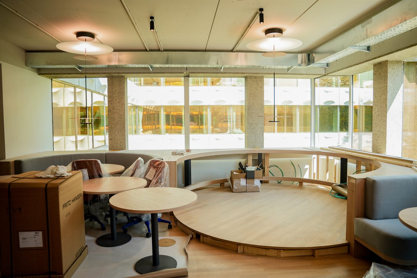 Dezelfde ruimte na oplevering: podium, banken en tafels