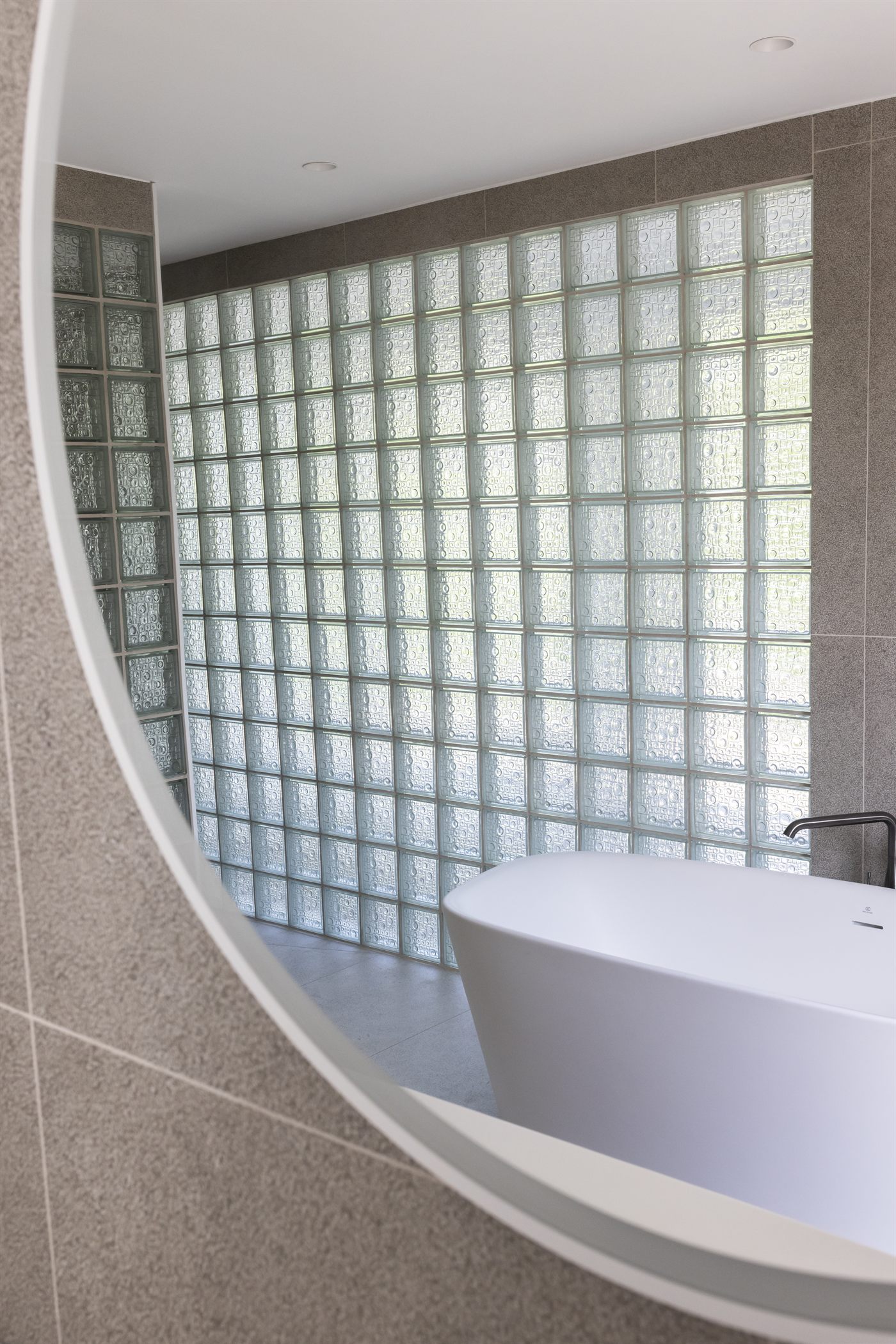 Baignoire îlot et miroir circulaire dans une salle d'eau en pierre